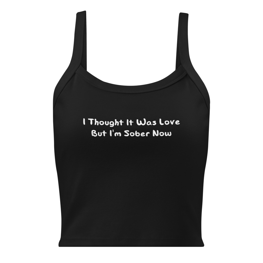 "I thought it was love but I’m sober now" printed on a solid black blend women's micro-rib tanktop laying on a flat surface