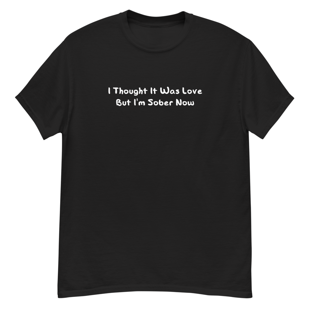 "I thought it was love but I’m sober now" printed on a black unisex classic tee laying on a flat surface