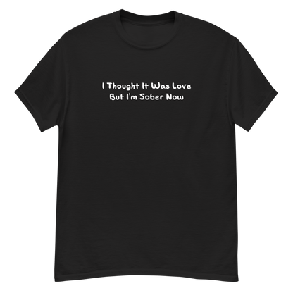 "I thought it was love but I’m sober now" printed on a black unisex classic tee laying on a flat surface