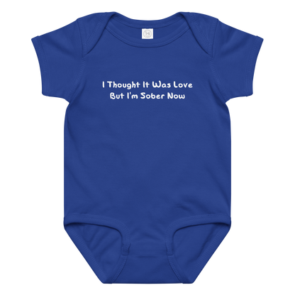 "I thought it was love but I’m sober now" printed on a royal baby jersey bodysuit laying on a flat surface amongst other clothes