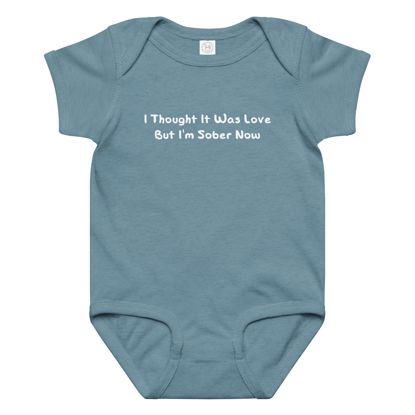 "I thought it was love but I’m sober now" printed on a vintage indigo baby jersey bodysuit laying on a flat surface amongst other clothes