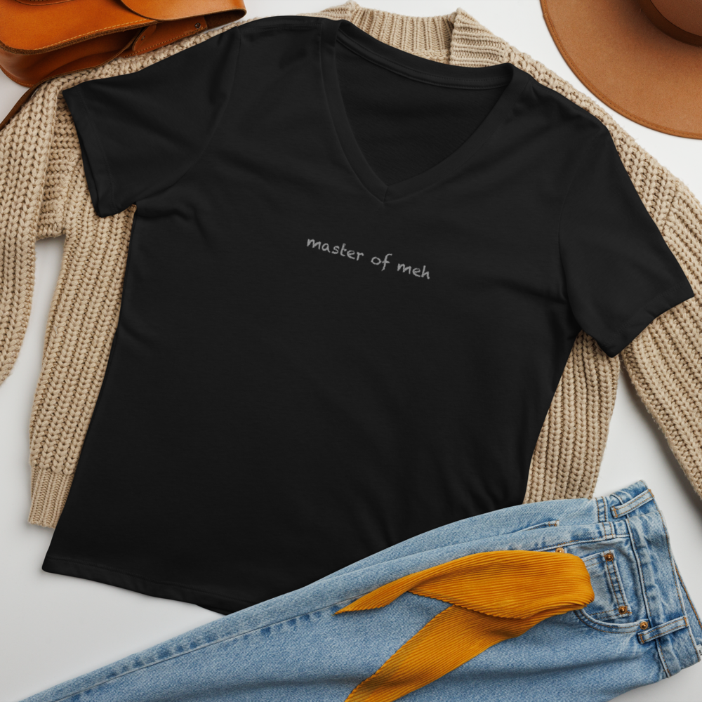 "Master of meh" printed on a solid black blend women's relaxed v-neck t-shirt laying on a flat surface amongst other clothes