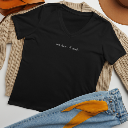 "Master of meh" printed on a solid black blend women's relaxed v-neck t-shirt laying on a flat surface amongst other clothes