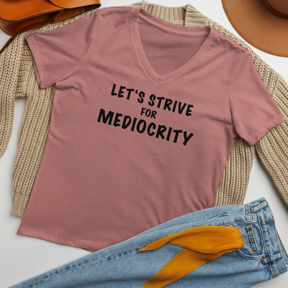 "Let's strive for mediocity" printed on a heather mauve women's relaxed v-neck t-shirt laying on a flat surface amongst other clothes