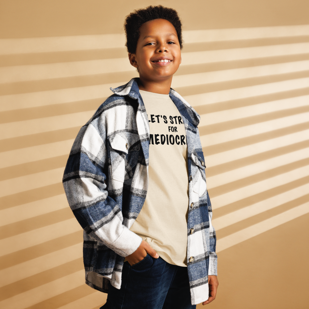 "Let's strive for mediocity" printed on a natural youth classic tee worn by a male also wearing a jacket