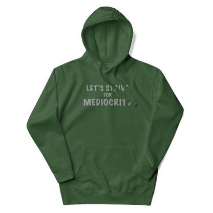 "Let's strive for mediocity" printed on a forest green unisex hoodie laying on a flat surface with the hood up
