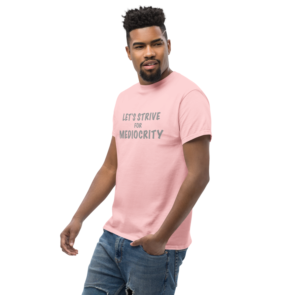 "Let's strive for mediocity" printed on a light pink unisex classic tee worn by a male