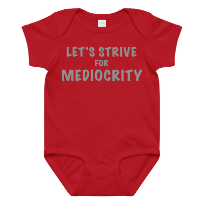 "Let's strive for mediocity" printed on a red baby jersey bodysuit laying on a flat surface amongst other clothes