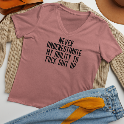 "Never Understimate My Ability To Fuck Shit Up" printed on a heather mauve women's relaxed v-neck t-shirt laying on a flat surface amongst other clothes