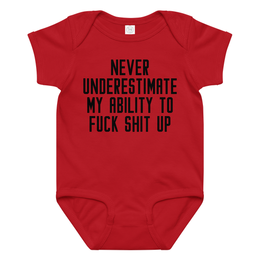 "Never Understimate My Ability To Fuck Shit Up" printed on a red baby jersey bodysuit laying on a flat surface amongst other clothes