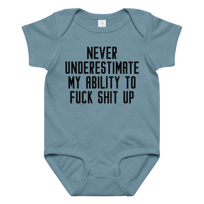 "Never Understimate My Ability To Fuck Shit Up" printed on a vintage indigo baby jersey bodysuit laying on a flat surface amongst other clothes