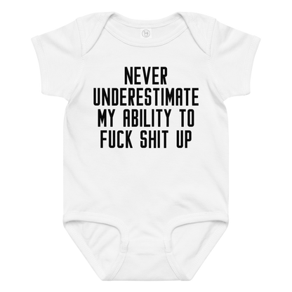 "Never Understimate My Ability To Fuck Shit Up" printed on a white baby jersey bodysuit laying on a flat surface amongst other clothes