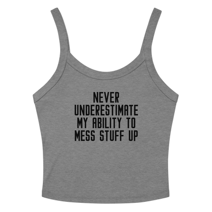 "Never Understimate My Ability To Mess Stuff Up" printed on a athletic heather women's micro-rib tanktop laying on a flat surface amongst sunglasses and shorts