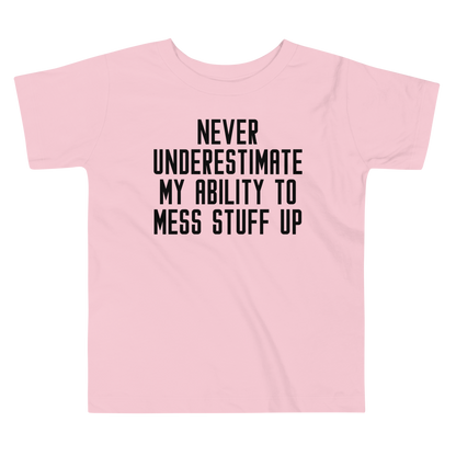"Never Understimate My Ability To Mess Stuff Up" printed on a pink toddler short sleeve tee laying on a flat surface