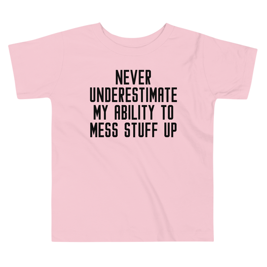 "Never Understimate My Ability To Mess Stuff Up" printed on a pink toddler short sleeve tee laying on a flat surface
