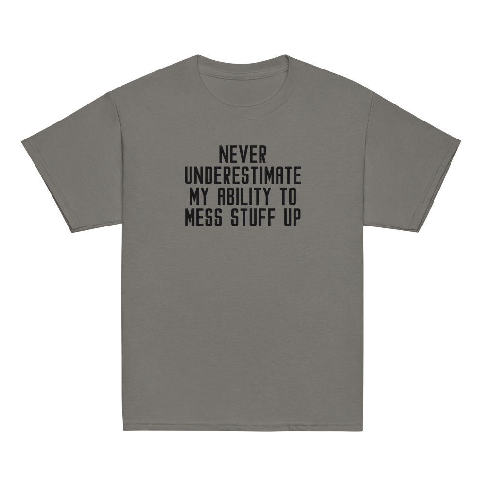 "Never Understimate My Ability To Mess Stuff Up" printed on a charcoal youth classic tee laying on a flat surface