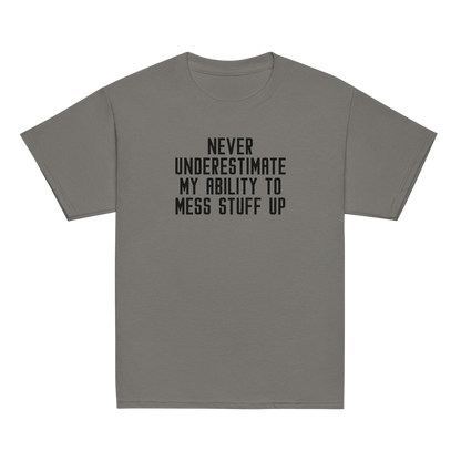"Never Understimate My Ability To Mess Stuff Up" printed on a charcoal youth classic tee laying on a flat surface