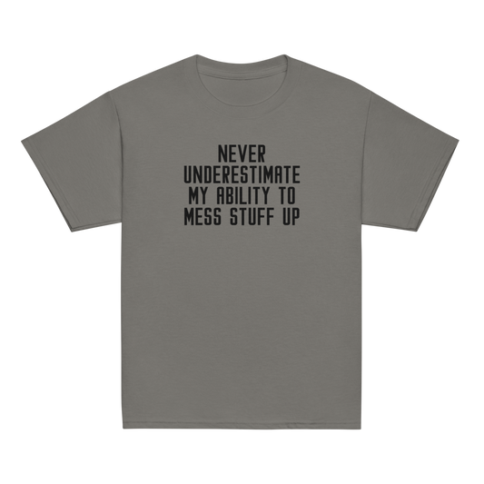 "Never Understimate My Ability To Mess Stuff Up" printed on a charcoal youth classic tee laying on a flat surface
