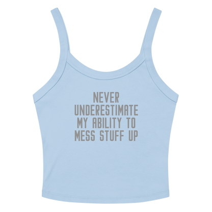 "Never Understimate My Ability To Mess Stuff Up" printed on a solid baby blue blend women's micro-rib tanktop laying on a flat surface amongst sunglasses and shorts