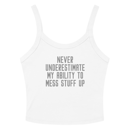 "Never Understimate My Ability To Mess Stuff Up" printed on a solid white blend women's micro-rib tanktop laying on a flat surface amongst sunglasses and shorts