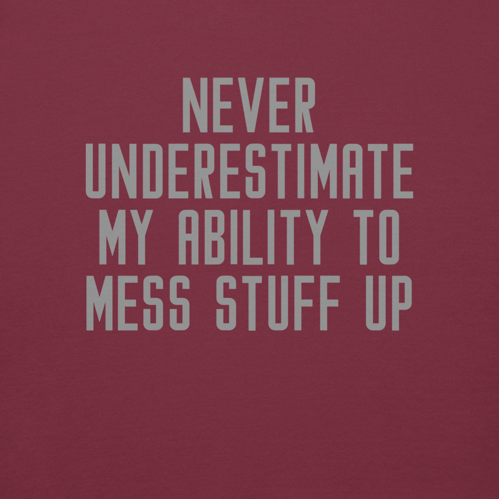 "Never Understimate My Ability To Mess Stuff Up" printed on a maroon background
