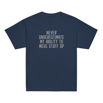 "Never Understimate My Ability To Mess Stuff Up" printed on a navy youth classic tee laying on a flat surface