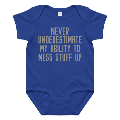 "Never Understimate My Ability To Mess Stuff Up" printed on a royal baby jersey bodysuit laying on a flat surface amongst other clothes
