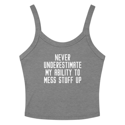 "Never Understimate My Ability To Mess Stuff Up" printed on a athletic heather women's micro-rib tanktop laying on a flat surface amongst sunglasses and shorts