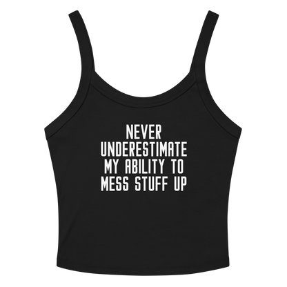 "Never Understimate My Ability To Mess Stuff Up" printed on a solid black blend women's micro-rib tanktop laying on a flat surface amongst sunglasses and shorts