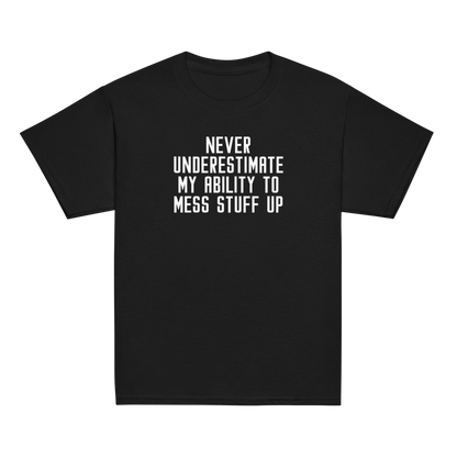 "Never Understimate My Ability To Mess Stuff Up" printed on a black youth classic tee laying on a flat surface
