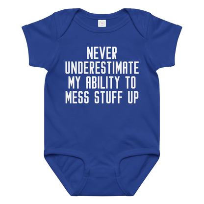 "Never Understimate My Ability To Mess Stuff Up" printed on a royal baby jersey bodysuit laying on a flat surface amongst other clothes
