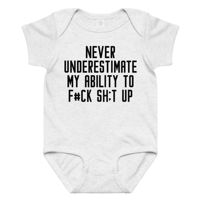 "Never Understimate My Ability To F#Ck Sh:t Up" printed on a ash baby jersey bodysuit laying on a flat surface amongst other clothes