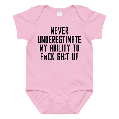 "Never Understimate My Ability To F#Ck Sh:t Up" printed on a pink baby jersey bodysuit laying on a flat surface amongst other clothes