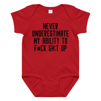 "Never Understimate My Ability To F#Ck Sh:t Up" printed on a red baby jersey bodysuit laying on a flat surface amongst other clothes