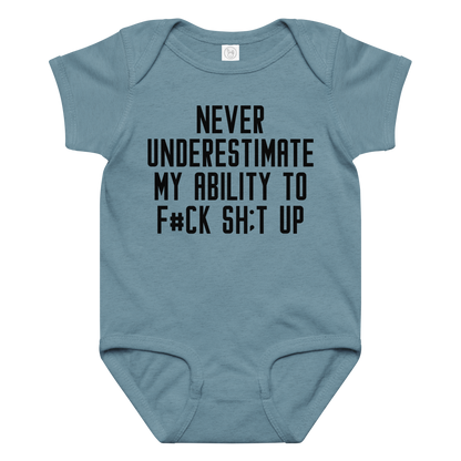"Never Understimate My Ability To F#Ck Sh:t Up" printed on a vintage indigo baby jersey bodysuit laying on a flat surface amongst other clothes