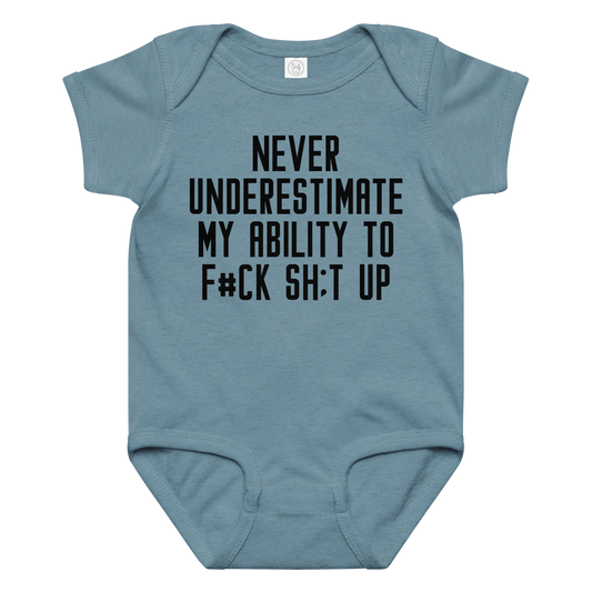 "Never Understimate My Ability To F#Ck Sh:t Up" printed on a vintage indigo baby jersey bodysuit laying on a flat surface amongst other clothes