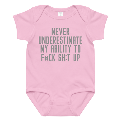 "Never Understimate My Ability To F#Ck Sh:t Up" printed on a pink baby jersey bodysuit laying on a flat surface amongst other clothes