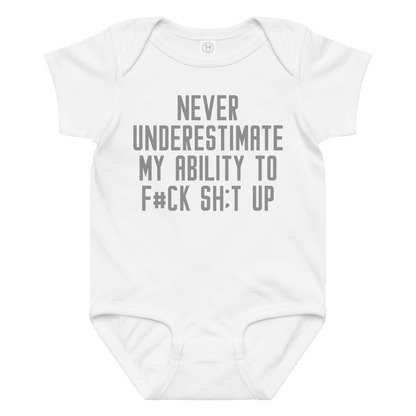 "Never Understimate My Ability To F#Ck Sh:t Up" printed on a white baby jersey bodysuit laying on a flat surface amongst other clothes