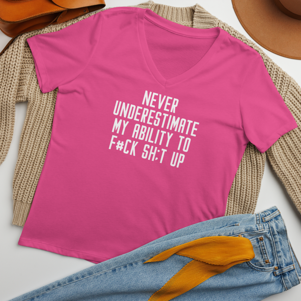 "Never Understimate My Ability To F#Ck Sh:t Up" printed on a berry women's relaxed v-neck t-shirt laying on a flat surface amongst other clothes