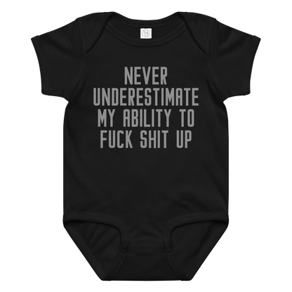 "Never Understimate My Ability To Fuck Shit Up" printed on a black baby jersey bodysuit laying on a flat surface amongst other clothes