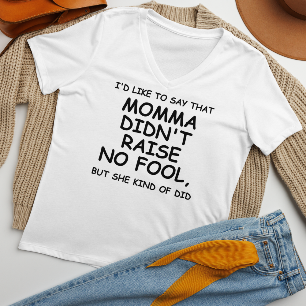 "I'd like to say that momma didn't raise no fool, but she kind of did" printed on a solid white blend women's relaxed v-neck t-shirt laying on a flat surface amongst other clothes