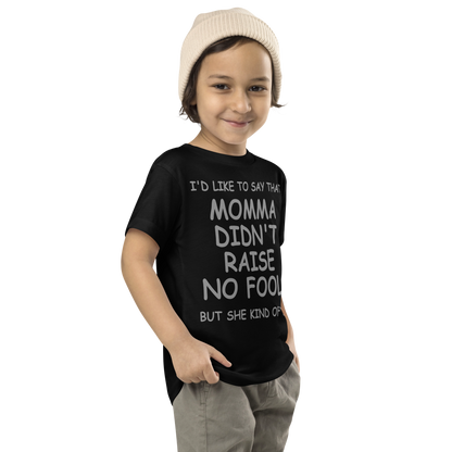 "I'd like to say that momma didn't raise no fool, but she kind of did" printed on a black toddler short sleeve tee worn by a male who is also wearing a knit cap