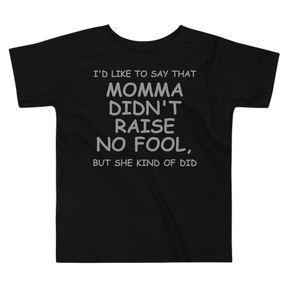 "I'd like to say that momma didn't raise no fool, but she kind of did" printed on a black toddler short sleeve tee laying on a flat surface
