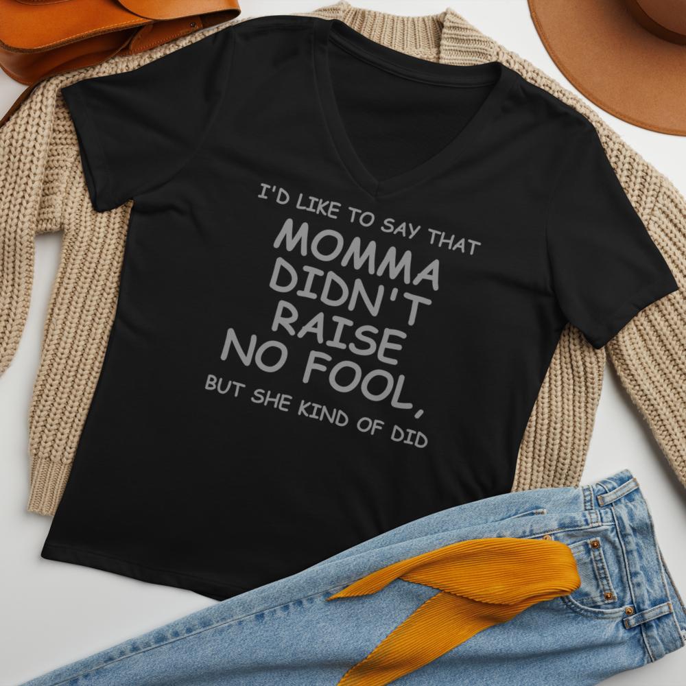 "I'd like to say that momma didn't raise no fool, but she kind of did" printed on a solid black blend women's relaxed v-neck t-shirt laying on a flat surface amongst other clothes