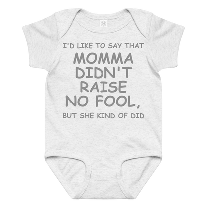 "I'd like to say that momma didn't raise no fool, but she kind of did" printed on a ash baby jersey bodysuit laying on a flat surface amongst other clothes