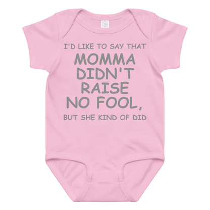"I'd like to say that momma didn't raise no fool, but she kind of did" printed on a pink baby jersey bodysuit laying on a flat surface amongst other clothes