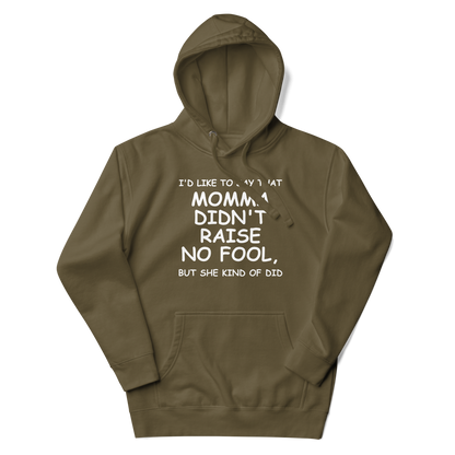 "I'd like to say that momma didn't raise no fool, but she kind of did" printed on a military green unisex hoodie laying on a flat surface with the hood up