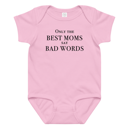 "Only the best moms say bad words" printed on a pink baby jersey bodysuit laying on a flat surface amongst other clothes
