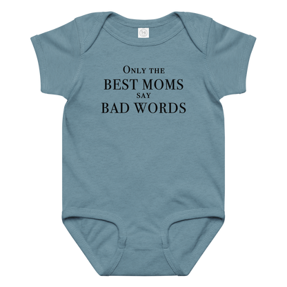 "Only the best moms say bad words" printed on a vintage indigo baby jersey bodysuit laying on a flat surface amongst other clothes