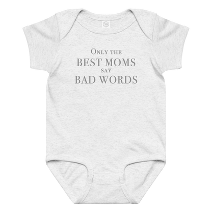 "Only the best moms say bad words" printed on a ash baby jersey bodysuit laying on a flat surface amongst other clothes